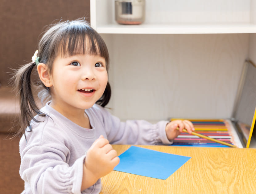 笑顔で色鉛筆と色紙を使っているお子さんの様子